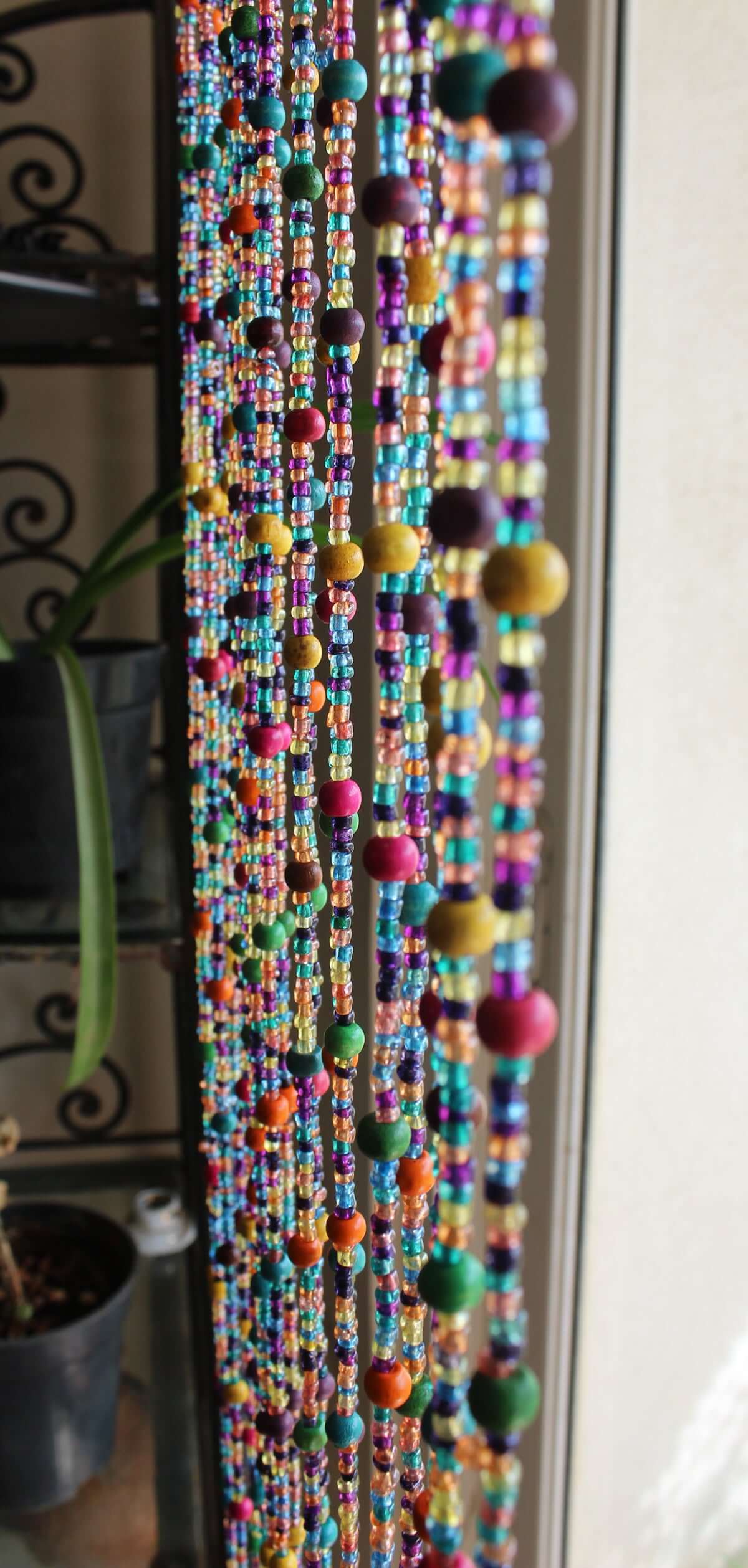 Handmade colorful glass bead strands with jingle bells—perfect for doorways or wall décor. Eco-friendly and crafted by women's artisans in India.